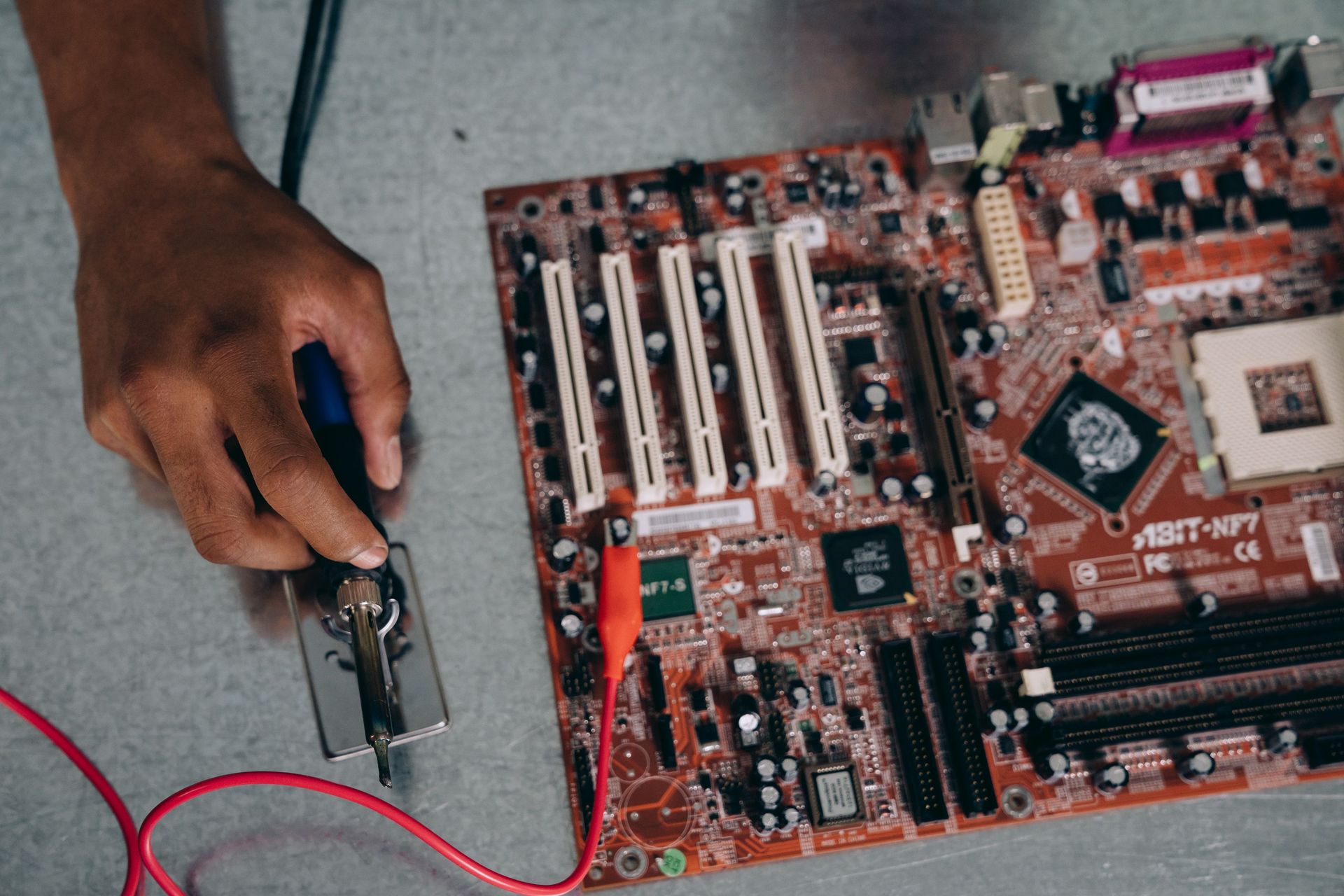 An engineer uses a soldering tool on a motherboard, showcasing technology and precision.