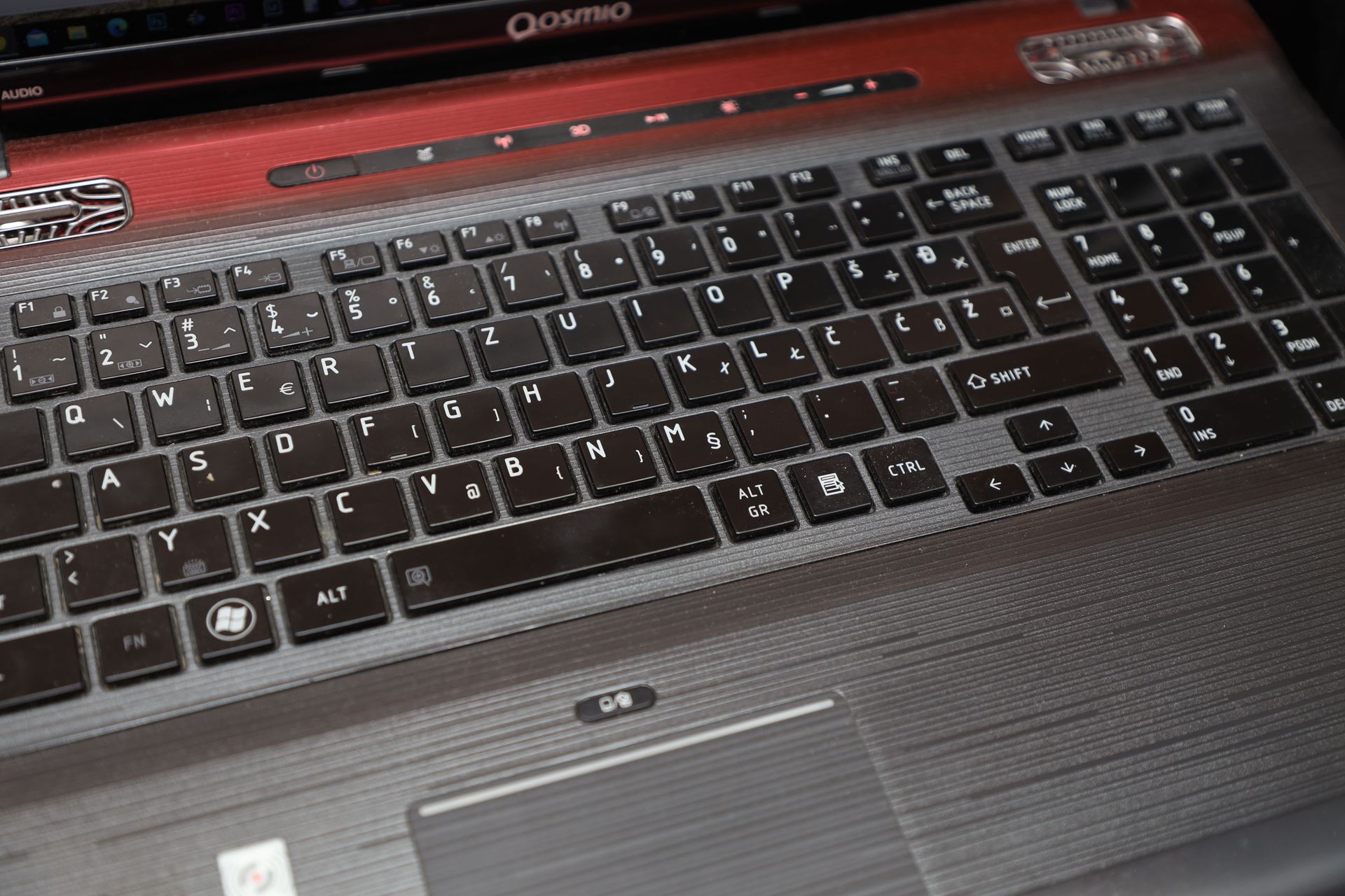 Detailed view of a vintage Qosmio laptop keyboard with a distinct European key layout.
