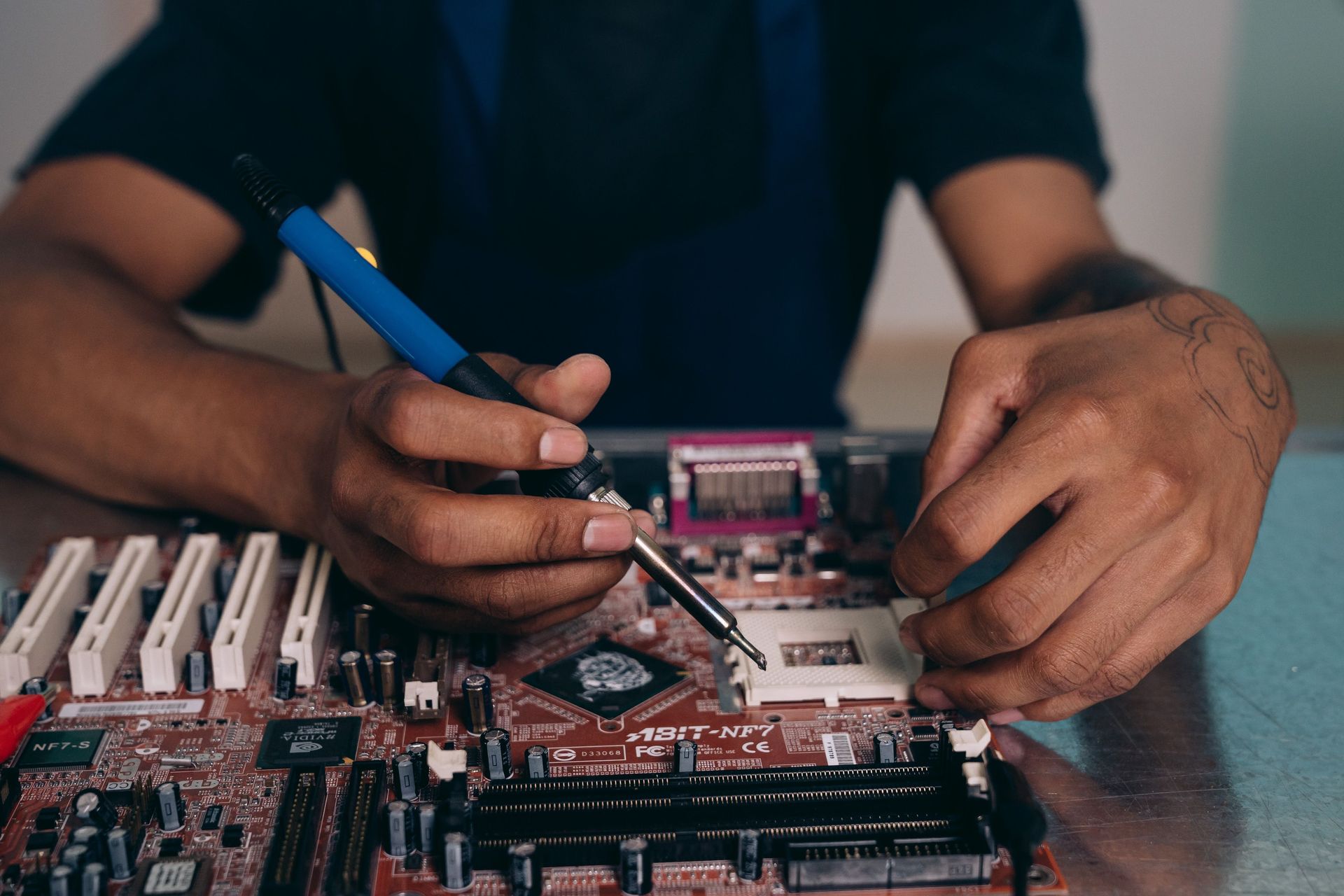 Engineer skillfully soldering components on a motherboard in a tech workshop.