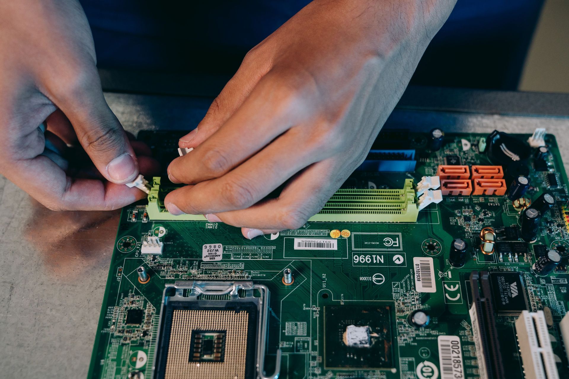 Hands carefully assembling a computer motherboard, showcasing technical craftsmanship in electronics.